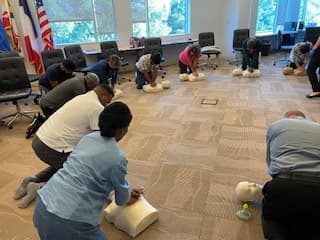 Employees practicing CPR compressions on training manikins during a live class.